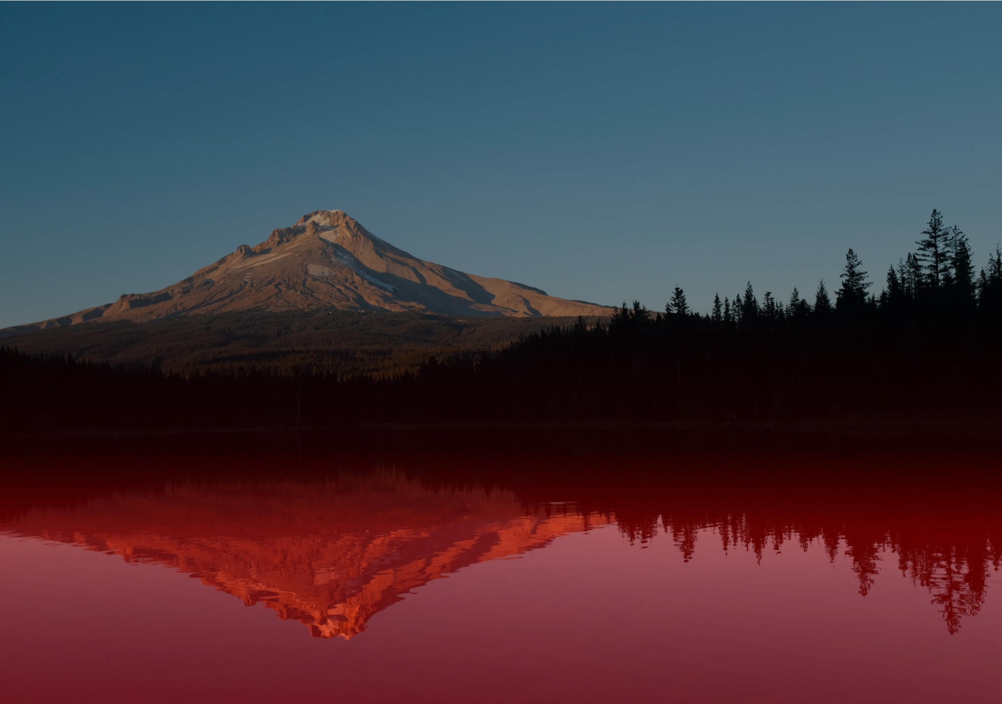 Image of a mountain with a reflection across a lake that glows red.